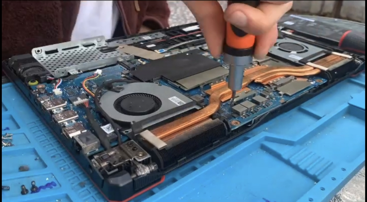 Desmontaje del sistema de refrigeración de un notebook sobre una superficie de trabajo azul